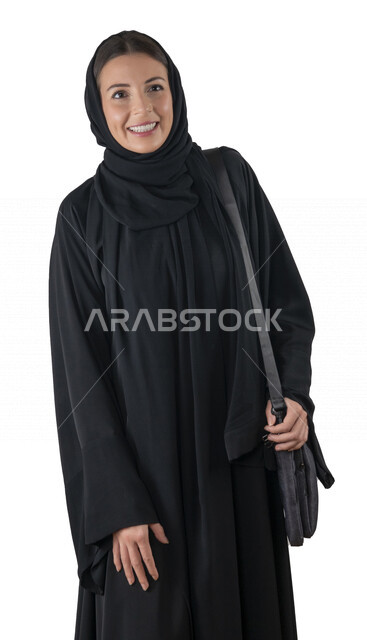 بورتريه لطالبة جامعية عربية إماراتيه خليجية محجبة مبتسمه تحمل حقيبة اللابتوب على كتفها, تنظر الى الكاميرا, موظفه في شركه إماراتيه, شابة متشوقة للذهاب الى العمل, خلفية بيضاء