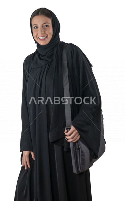 بورتريه لطالبة جامعية عربية إماراتيه خليجية محجبة مبتسمه تحمل حقيبة اللابتوب على كتفها, تنظر الى الكاميرا, موظفه في شركه إماراتيه, شابة متشوقة للذهاب الى العمل, خلفية بيضاء