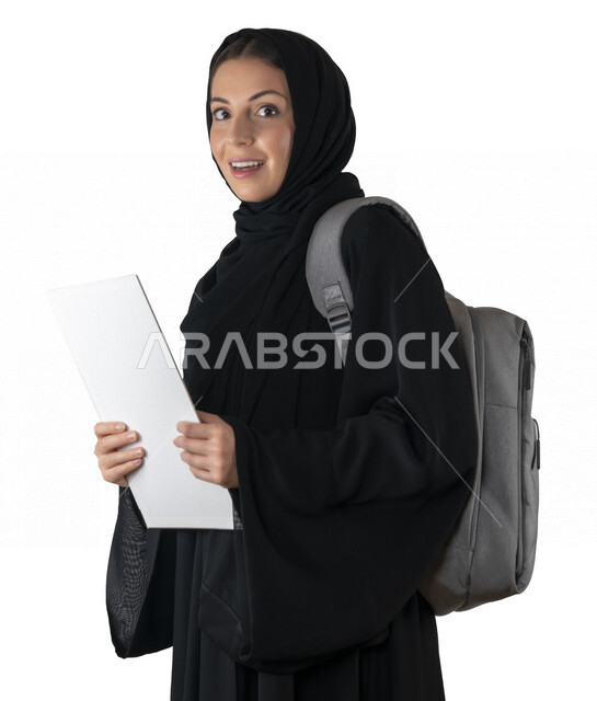 بورتريه لطالبة جامعية عربية إماراتيه خليجية محجبة مبتسمه تحمل حقيبة على كتفها, تمسك بيدها كتب جامعية, تنظر الى الكاميرا, الاستعداد للعام الدراسي الجامعي الجديد, شابة متشوقة للذهاب الى الجامعه, مدارس وجامعات, التعليم في الإمارات, خلفية بيضاء