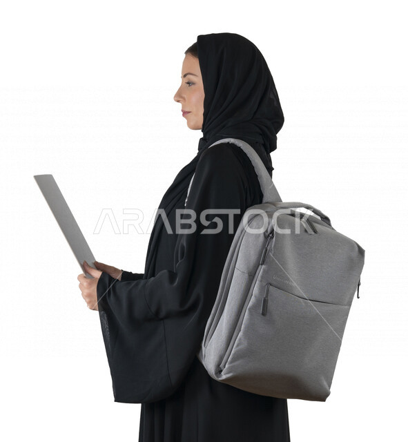 بورتريه من الجانب لطالبة جامعية عربية إماراتيه خليجية محجبة تحمل حقيبة على كتفها, تمسك بيدها أوراق جامعية, الاستعداد للعام الدراسي الجامعي الجديد, شابة متشوقة للذهاب الى الجامعه, مدارس وجامعات, التعليم في الإمارات, خلفية بيضاء