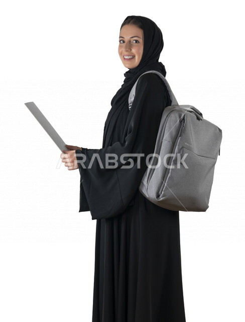بورتريه لطالبة جامعية عربية إماراتيه خليجية محجبة مبتسمه تحمل حقيبة على كتفها, تمسك بيدها أوراق جامعية, تنظر الى الكاميرا, الاستعداد للعام الدراسي الجامعي الجديد, شابة متشوقة للذهاب الى الجامعه, مدارس وجامعات, التعليم في الإمارات, خلفية بيضاء