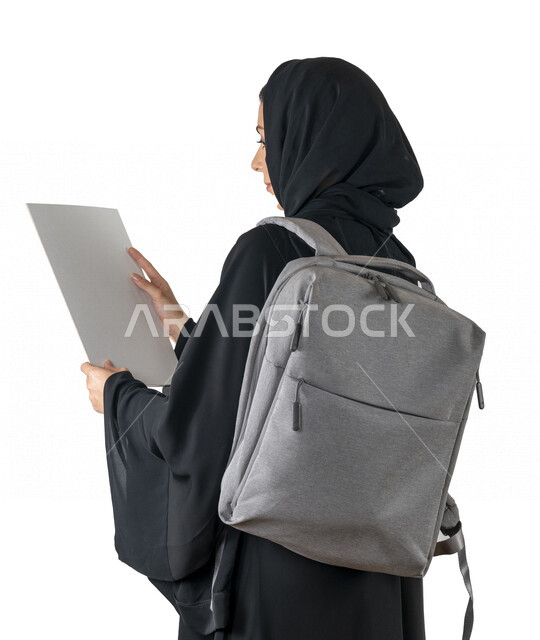 بورتريه من الجانب لطالبة جامعية عربية إماراتيه خليجية محجبة تحمل حقيبة على كتفها, تمسك بيدها أوراق جامعية, الاستعداد للعام الدراسي الجامعي الجديد, شابة متشوقة للذهاب الى الجامعه, مدارس وجامعات, التعليم في الإمارات, خلفية بيضاء