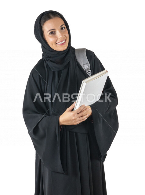 بورتريه لطالبة جامعية عربية إماراتيه خليجية محجبة مبتسمه تحمل حقيبة على كتفها, تمسك بيدها كتب جامعية, تنظر الى الكاميرا, الاستعداد للعام الدراسي الجامعي الجديد, شابة متشوقة للذهاب الى الجامعه, مدارس وجامعات, التعليم في الإمارات, خلفية بيضاء