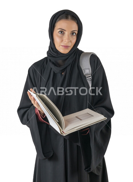 بورتريه لطالبة جامعية عربية إماراتيه خليجية محجبة مبتسمه تحمل حقيبة على كتفها, تمسك بيدها كتب جامعية, تنظر الى الكاميرا, الاستعداد للعام الدراسي الجامعي الجديد, شابة متشوقة للذهاب الى الجامعه, مدارس وجامعات, التعليم في الإمارات, خلفية بيضاء