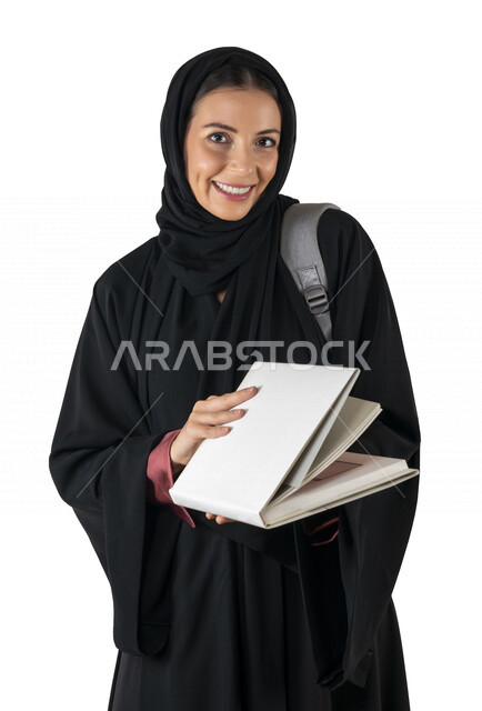بورتريه لطالبة جامعية عربية إماراتيه خليجية محجبة مبتسمه تحمل حقيبة على كتفها, تمسك بيدها كتب جامعية, تنظر الى الكاميرا, الاستعداد للعام الدراسي الجامعي الجديد, شابة متشوقة للذهاب الى الجامعه, مدارس وجامعات, التعليم في الإمارات, خلفية بيضاء