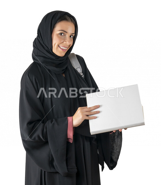 بورتريه لطالبة جامعية عربية إماراتيه خليجية محجبة مبتسمه تحمل حقيبة على كتفها, تمسك بيدها كتب جامعية, تنظر الى الكاميرا, الاستعداد للعام الدراسي الجامعي الجديد, شابة متشوقة للذهاب الى الجامعه, مدارس وجامعات, التعليم في الإمارات, خلفية بيضاء