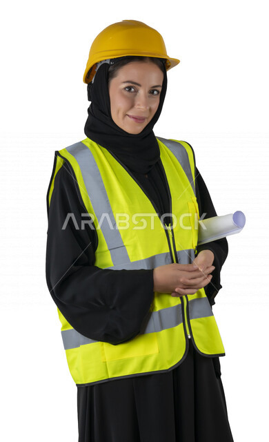 بورتريه لمهندسة معمارية عربية إماراتيه خليجية مبتسمه تحمل بيدها مخطط البناء، تنظر إلى الكاميرا, مهندسة إنشاءات محجبة ترتدي بدلة وخوذة السلامة في العمل, مهن ووظائف هندسيه، مشروع بناء، مفهوم الهندسه المعماريه, خلفية بيضاء