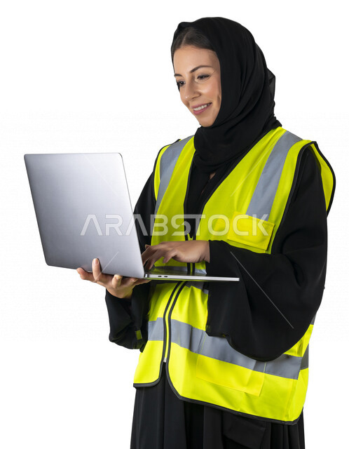 بورتريه لمهندسة معمارية عربية إماراتيه خليجية تحمل بيدها جهاز اللابتوب المحمول ، مهندسة إنشاءات محجبة ترتدي بدلة السلامة في العمل، مهن ووظائف هندسيه، مشروع بناء، مفهوم الهندسه المعماريه, خلفية بيضاء