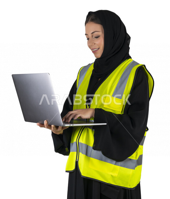 بورتريه لمهندسة معمارية عربية إماراتيه خليجية تحمل بيدها جهاز اللابتوب المحمول ، مهندسة إنشاءات محجبة ترتدي بدلة السلامة في العمل، مهن ووظائف هندسيه، مشروع بناء، مفهوم الهندسه المعماريه, خلفية بيضاء