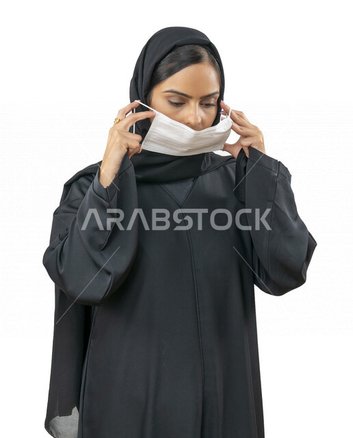 Portrait of a young Arab Gulf Emirati woman wearing a muzzle to avoid the spread of the virus, following protection and safety measures, avoiding the spread of infection, Corona, white background