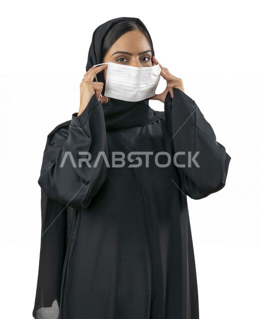 بورتريه لشابة عربية خليجية اماراتية تقوم بارتداء الكمامة لتجنب تفشي الفايروس ، اتباع اجراءات الحماية والسلامة ، تجنب انتشار العدوى ، كورونا , خلفية بيضاء