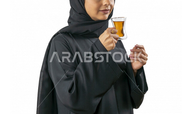 بورتريه لمرأة عربية خليجية إماراتية ترتدي العباءة , تقوم باحتساء أعشاب الشاي الساخن , الإستمتاع بالمشروبات الدافئة , تقديم الضيافة , قضاء وقت ممتع و هادئ , خلفية بيضاء . 