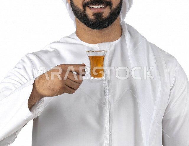 بورتريه لرجل عربي خليجي إماراتي مبتسم يرتدي الزي الإماراتي التقليدي , يحمل بيده كوب من الشاي الأحمر, إحتساء الشاي الساخن , الإستمتاع بالمشروبات الدافئة , أعشاب الشاي , قضاء وقت ممتع و هادئ , خلفية بيضاء, الضيافه السعوديه, مشروبات ساخنه