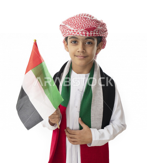 الإحتفال بيوم الاستقلال الوطني لدولة الإمارات العربية المتحدة, بورتريه مقرب لولد عربي خليجي اماراتي يرتدي العمامه والكندوره الاماراتية يحمل بيده ويرتدي علم الإمارات, إيماءات الفرح والسعادة, هوية اليوم الوطني الإماراتي51, الولاء والحب للوطن, خلفية بيضاء