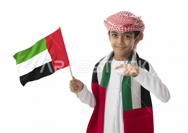 الإشاره الى العلم, الولاء والحب للوطن, الإحتفال بيوم الاستقلال الوطني لدولة الإمارات العربية المتحدة, بورتريه مقرب لولد عربي خليجي اماراتي يرتدي الزي التقليدي الاماراتي يرفع علم الإمارات, إيماءات الفرح والسعادة, هوية اليوم الوطني الإماراتي51, خلفية بيضاء