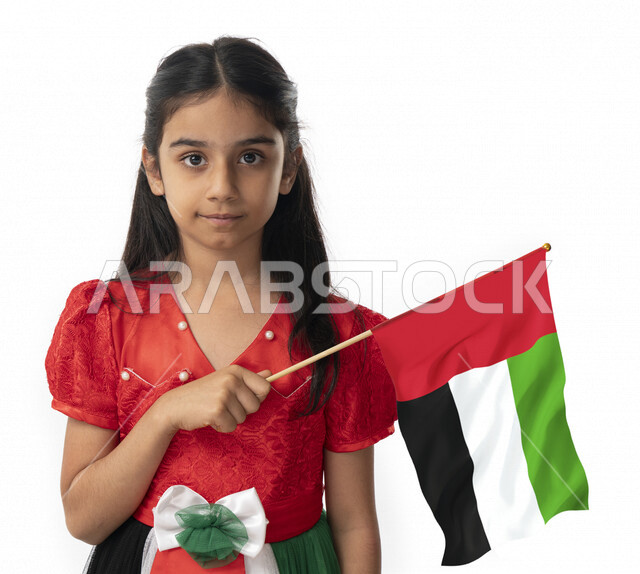تقديم الولاء والحب للوطن, الإحتفال بيوم الاستقلال لدولة الإمارات العربية المتحدة, بورتريه مقرب لبنت عربية خليجية إماراتية ترتدي فستان بألوان علم الإمارات, هوية اليوم الوطني الإماراتي51, فتاة تحمل بيدها علم الامارات وتنظر الى الكاميرا, خلفية بيضاء