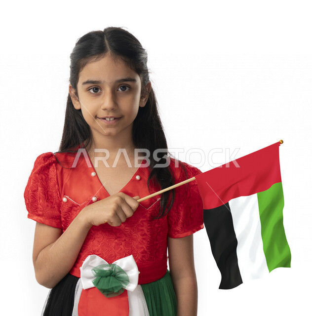 الإحتفال بيوم الاستقلال لدولة الإمارات العربية المتحدة, بورتريه مقرب لبنت عربية خليجية إماراتية ترتدي فستان بألوان علم الإمارات, هوية اليوم الوطني الإماراتي51, فتاة تحمل بيدها علم الامارات وتنظر الى الكاميرا, تقديم الولاء والحب للوطن, خلفية بيضاء