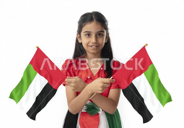النظر إلى الكاميرا, فتاة تحمل بيدها علم الامارات, الإحتفال بيوم الاستقلال لدولة الإمارات العربية المتحدة, بورتريه مقرب لبنت عربية خليجية إماراتية ترتدي فستان بألوان علم الإمارات, هوية اليوم الوطني الإماراتي51, تقديم الولاء والحب للوطن, خلفية بيضاء