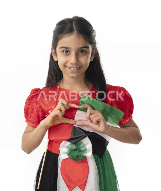 ايماءات يد على شكل قلب, الإحتفال بيوم الاستقلال لدولة الإمارات العربية المتحدة, بورتريه مقرب لبنت عربية خليجية إماراتية ترتدي فستان بألوان علم الإمارات وتنظر إلى الكاميرا, هوية اليوم الوطني الإماراتي51, تقديم الولاء والحب للوطن, خلفية بيضاء