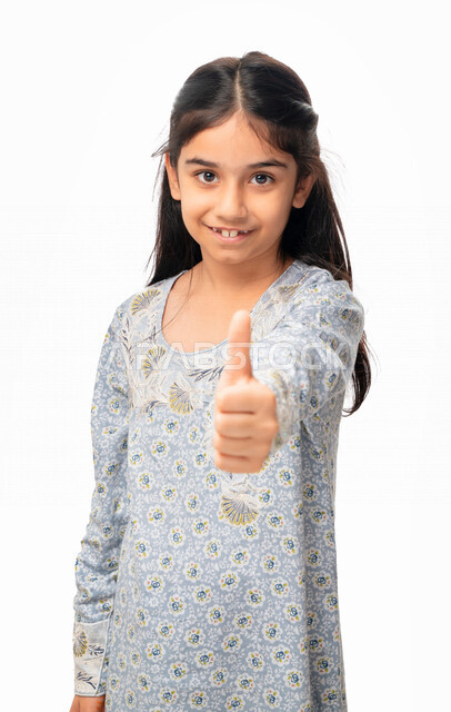 علامة الجودة, مفهوم الحالة الجيدة, بورتريه لفتاة عربية اماراتية خليجية ترفع اصبع الابهام الى الاعلى ،إيماءات وجه ويدين تدل على الإعجاب والرضى, الموافقه والقبول, بنت سعودية ترتدي الثوب الخليجي وتشعر بالإمتياز والتميز, خلفية بيضاء