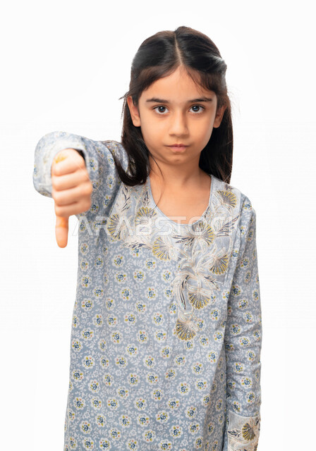 عدم القبول و الرفض, الفشل والخسارة , بورتريه مقرب لفتاة عربية اماراتية خليجية تشير بأصبع الابهام الى الاسفل ، حركات يد تدل على عدم الموافقه و عدم الإعجاب, بنت سعودية ترتدي الثوب الخليجي وتشعر بالإنزعاج من شيء ما، خلفية بيضاء