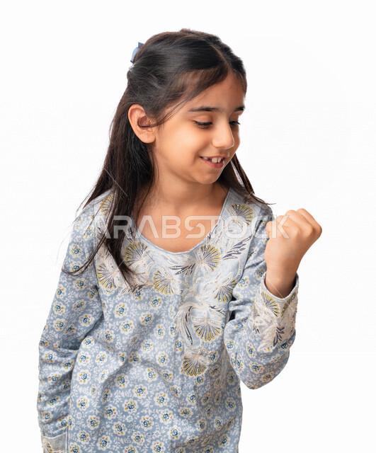 تحقيق الاهداف و إنجاز المهامات , الشعور بالسعاده و الرضا و الإعجاب، بورتريه مقرب لفتاة سعودية ترتدي الثوب الخليجي بايماءات وجه ويدين تدل على الفوز والإنتصار, بنت اماراتية عربية خليجية تشير بعلامة الكسب والقوه, خلفية بيضاء