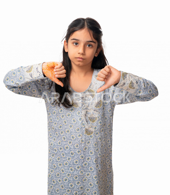  الرفض و عدم القبول, الخسارة والفشل ،بورتريه مقرب لفتاة عربية اماراتية خليجية تشير بأصبع الابهام الى الاسفل ، حركات يد تدل على عدم الموافقه و عدم الإعجاب, بنت سعودية ترتدي الثوب الخليجي وتشعر  بالإنزعاج من شيء ما، خلفية بيضاء