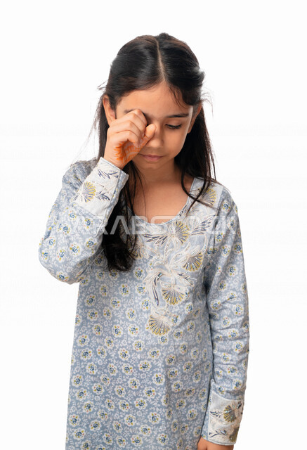 Feeling pain in the eye, undergoing a medical examination, regretting something and wanting to cry, a portrait of an Arab Emirati Gulf girl with facial movements and hands indicating a sense of disappointment, sadness and frustration, a Saudi girl wearing