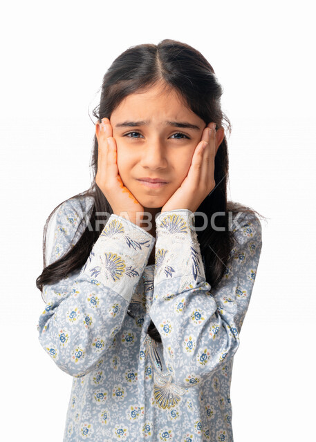 Sadness, frustration and the desire to cry, facial and hand gestures indicating a feeling of disappointment, a close-up portrait of an Arab Emirati girl placing her hands on her cheeks, a Saudi girl wearing a Gulf dress regretting something, loss and fail