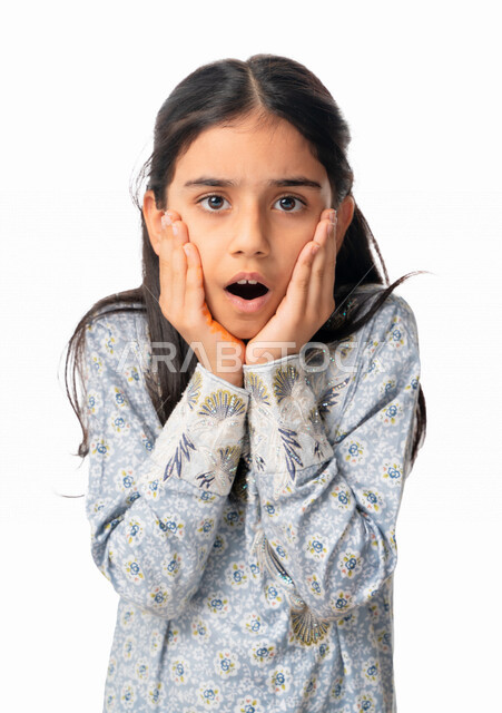 الذهول و الصدمة و الإستغراب، بورتريه مقرب لفتاة عربيه اماراتية خليجيه تضع يديها على وجنتيها  بإيماءات وجه ويدين تدل على الدهشه و التعجب, بنت سعودية ترتدي الثوب الخليجي و تتفاجئ من شيئ ما, خلفية بيضاء