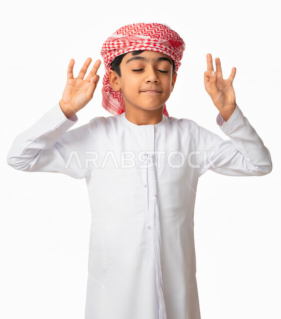 ممارسة تمارين رياضة اليوغا ، بورتريه لولد عربي اماراتي يرتدي العمامة والكندورة الاماراتية و يغمض عينيه و يرفع يديه إلى الأعلى بإيماءات و تعابير وجه و يدين تدل التأمل و الاسترخاء ، تمرين التنفس العميق ، خلفية بيضاء