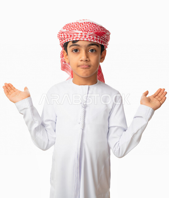 التفكير و التساؤل، إيماءات و تعابير تدل على الحيرة و الدهشة ،بورتريه لولد عربي اماراتي سعودي يرتدي الكندورة والعمامة الاماراتية  يرفع يديه عاليا بإستغراب ،خلفية بيضاء