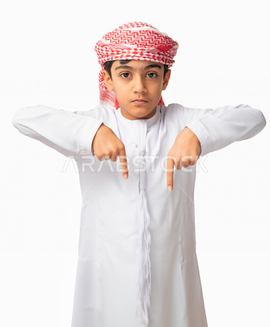  في هذه اللحظه (الآن), إيماءات يدين تشير الى موقع معين, بورتريه لولد عربي اماراتي خليجي يرتدي الكندورة والعمامة الاماراتية ويشير بأصابعه إلى الاسفل, حركات تدل على هذا المكان (هنا), خلفية بيضاء