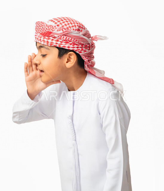 التحدث بصوت منخفض ، بورتريه مقرب لولد عربي اماراتي خليجي يرتدي العمامة والكندورة الاماراتية و يهمس خلف يده سرا، كتمان وحفظ الاسرار، مشاركة سر ما ،الهمس والهدوء اثناء الكلام، خلفية بيضاء