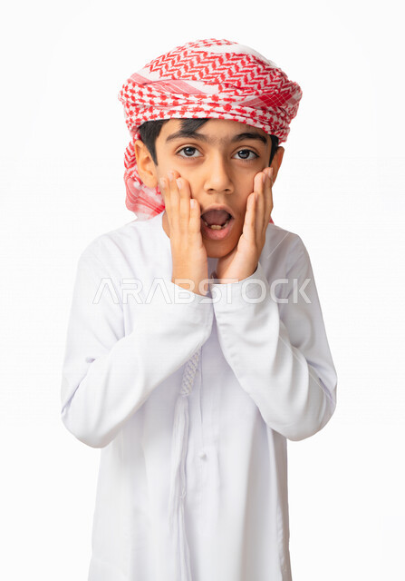 إيماءات وجه ويدين تدل على الدهشه, بورتريه مقرب لولد عربي اماراتي خليجي يرتدي الكندورة والعمامة الاماراتية يضع يديه على وجنتيه، التعجب و الإستغراب و التفاجؤ من شيئ ما, الصدمه والذهول، خلفية بيضاء