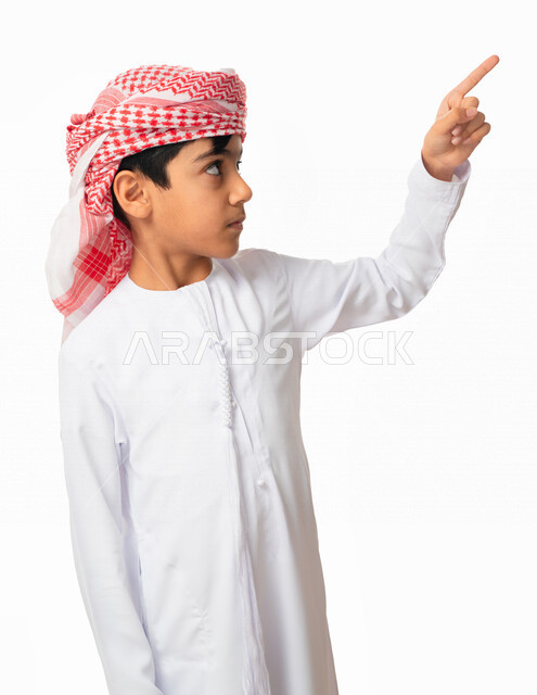 استخدام حاسة اللمس لتحريك العناصر الهولوجراميه, بورتريه مقرب لولد عربي اماراتي خليجي يرتدي العمامة و الكندورة الاماراتبة بإيماءات يدين تشير الى شيء ما, النقر على الشاشه, الشعور بالإعجاب والرضى, البهجه والسرور، خلفية بيضاء