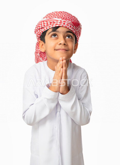 طلب المغفره من الله تعالى، إيماءات وجه ويدين تدل على الخشوع و الدعاء والتضرع الى الله, بورتريه مقرب لولد عربي اماراتي خليجي يرتدي الكندورة والعمامة الاماراتية , الحمد والشكر و طلب العون, الرغبه في تحقيق الأمنيات, خلفية بيضاء