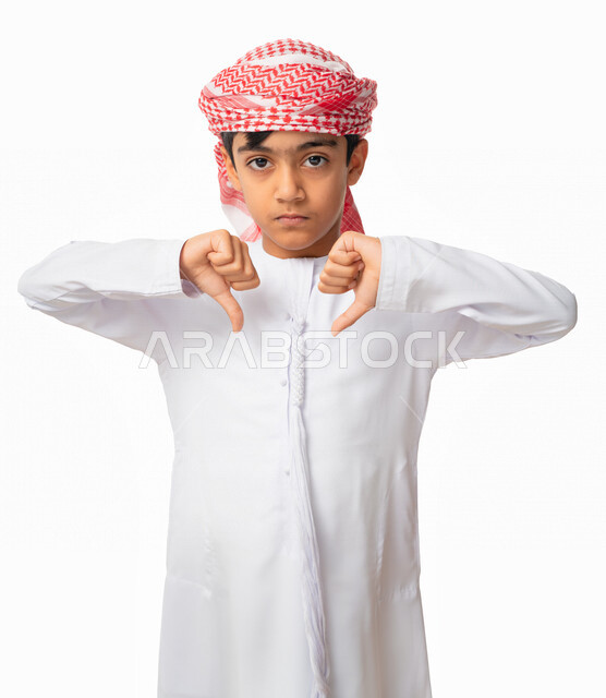 عدم الرغبة و الإنزعاج من شيء ما، بورتريه لولد عربي اماراتي خليجي يرتدي الكندورة والعمامة الاماراتية, ايماءات يد تدل على عدم الموافقه و عدم الإعجاب, الرفض و عدم القبول, أصبع الإبهام للاسفل، خلفية بيضاء