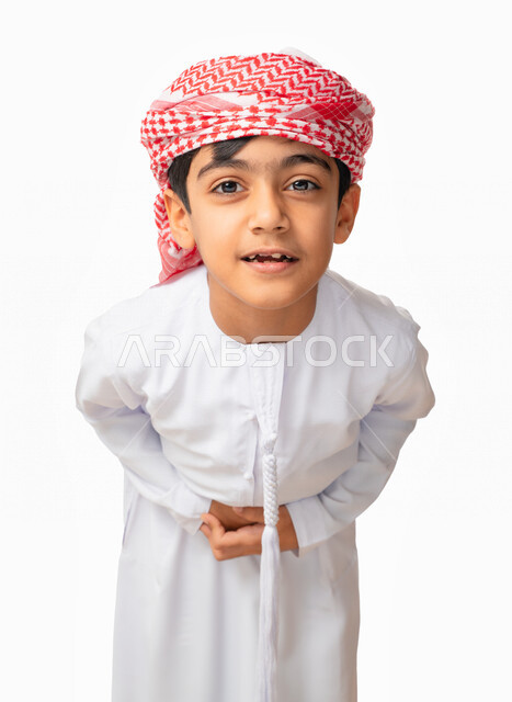عسر الهضم والشعور بحرقة في المعدة، بورتريه مقرب لولد عربي اماراتي خليجي يرتدي الكندورة والعمامة الاماراتية ينظر الى الكاميرا، إيماءات وجه ويدين تدل على الشعور بألم في البطن, الإحساس بالمغص و التعب والإرهاق, طلب المساعده للذهاب الى الطبيب، خلفية بيضاء