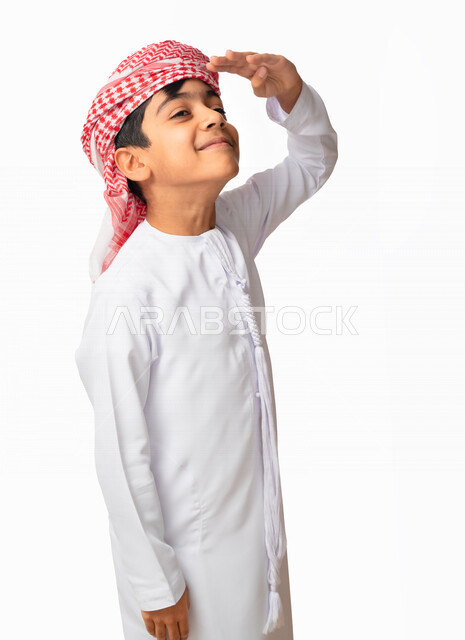 تعابير الوجه ولغة الجسد المختلفة, بورتريه مقرب لولد عربي اماراتي خليجي يرتدي الكندورة والعمامة الاماراتية, رفع اليد اليسرى لإلقاء التحية, ايماءات تدل على السعادة , مفهوم السلام والترحيب, خلفية بيضاء