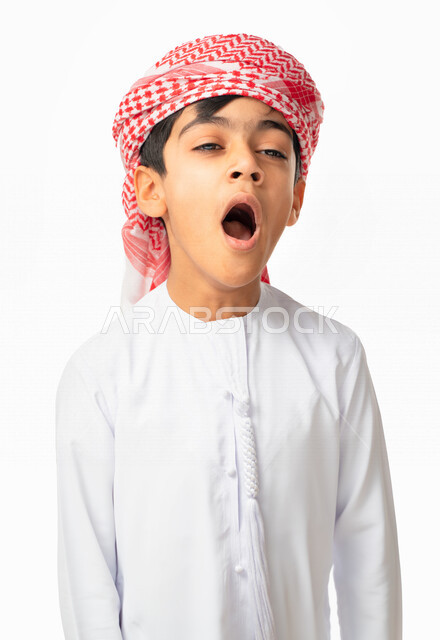 الإحساس بالإرهاق و الحاجه الى النوم والراحه ,بورتريه  لولد عربي اماراتي خليجي يرتدي الكندورة والعمامة بإيماءات وجه ويدين تدل على النعاس, التثاؤب و الشعور بالتعب, الكسل والخمول, خلفية بيضاء