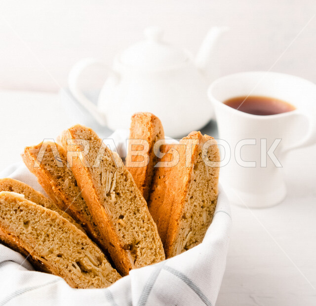 Close-up of a plate of toasted bread slices with a cup of tea, hot drinks, fresh baked goods and pastries, delicious biscuit bread