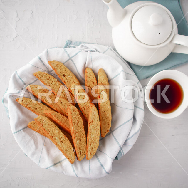 Close-up of a plate of toasted bread slices with a cup of tea, hot drinks, fresh baked goods and pastries, delicious biscuit bread