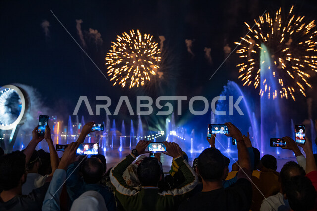 صورة من الخلف لمجموعة من السياح يقومو بتصوير الالعاب النارية في افتتاح كاس العالم في قطر من خلال الهواتف المحمولة، مفرقعات نارية، فعاليات افتتاح كأس العالم في قطر 2022، بطولة كأس العالم، فيفا 2022، مونديال قطر، السياحة في قطر