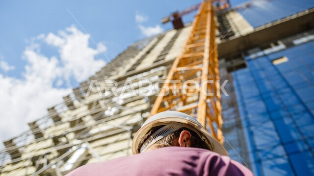 A picture from below of an architect standing in front of the engineering construction site for an architectural building, real estate development, new projects, urban and engineering development, residential building and contracting, construction site