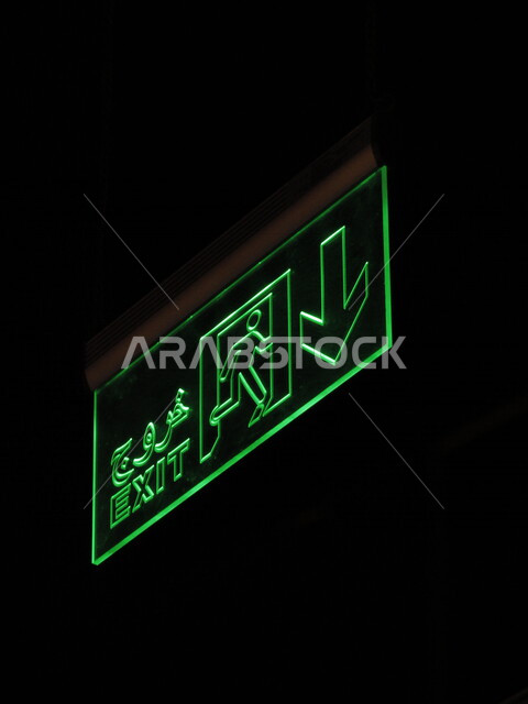 لوحة مضيئة باللون الأخضر معلقة على السقف مكتوب عليها خروج ، مكان للخروج ، لوحة إرشادية ، توجيه إلى المخرج