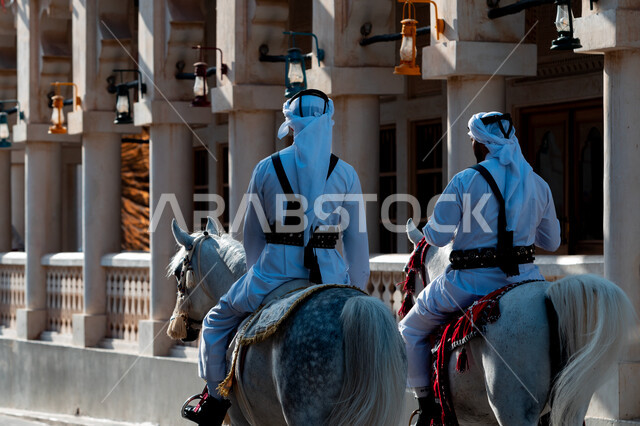 زاوية من الخلف لرجلان عربيان خليجيان قطريان يمتطيان الخيل العربي الأصيل ، الزي القطري التقليدي ، ترويض الخيل ، أنشطة وفعاليات 