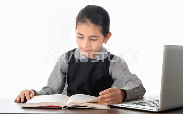 المثابرة والإصرار على النحاج والتفوق، بورتريه لطالبة عربية خليجية اماراتية ترتدي الزي المدرسي تقوم بمتابعة الدروس باستخدام الكمبيوتر، التحضير الجيد للاختبار، تلميذة سعودية تتابع دراستها عن طريق المنصات الدراسية الإلكترونية، خلفية بيضاء