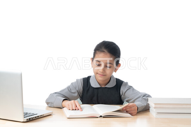 متابعة الدراسة عن طريق المنصات الدراسية الإلكترونية، بورتريه لطالبة عربية خليجية اماراتية ترتدي الزي المدرسي تقوم بتحضير الدروس باستخدام الكمبيوتر، تلميذة سعودية مجتهدة تجلس على طاولة الدراسة وتحفظ دروسها، مفهوم التعليم الإلكتروني، خلفية بيضاء