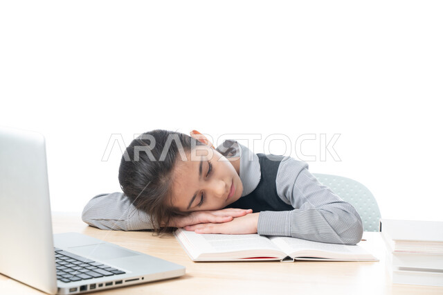 النوم على طاولة الدراسة، ايماءات النعاس والتعب والإرهاق، بورتريه لطالبة عربية خليجية اماراتية ترتدي اليونيفورم المدرسي تقوم بإهمال دروسها، سلبيات التعلم عن بعد، تلميذة سعودية غير محبة للدراسة، هدر وضياع الوقت، خلفية بيضاء